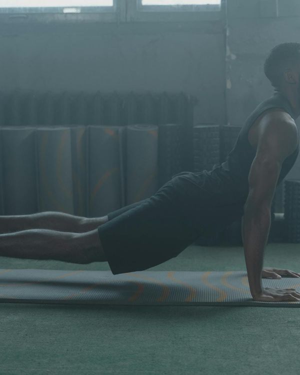A focused male athlete stretching on a yoga mat in a minimalist gym.